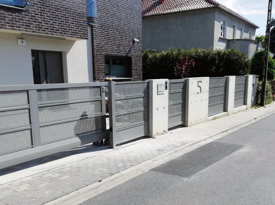 Alfen, model F01: Brama i przęsła F01 z szerokich pełnych paneli przy domu z cegły