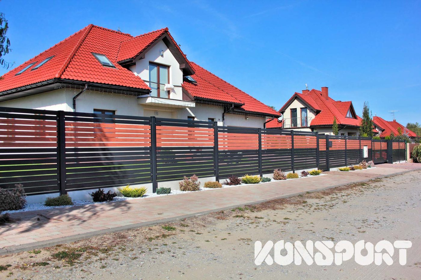 Konsport: Długi odcinek ogrodzenia z lameli w antracycie i kolorze drewna wzdłuż ulicy
