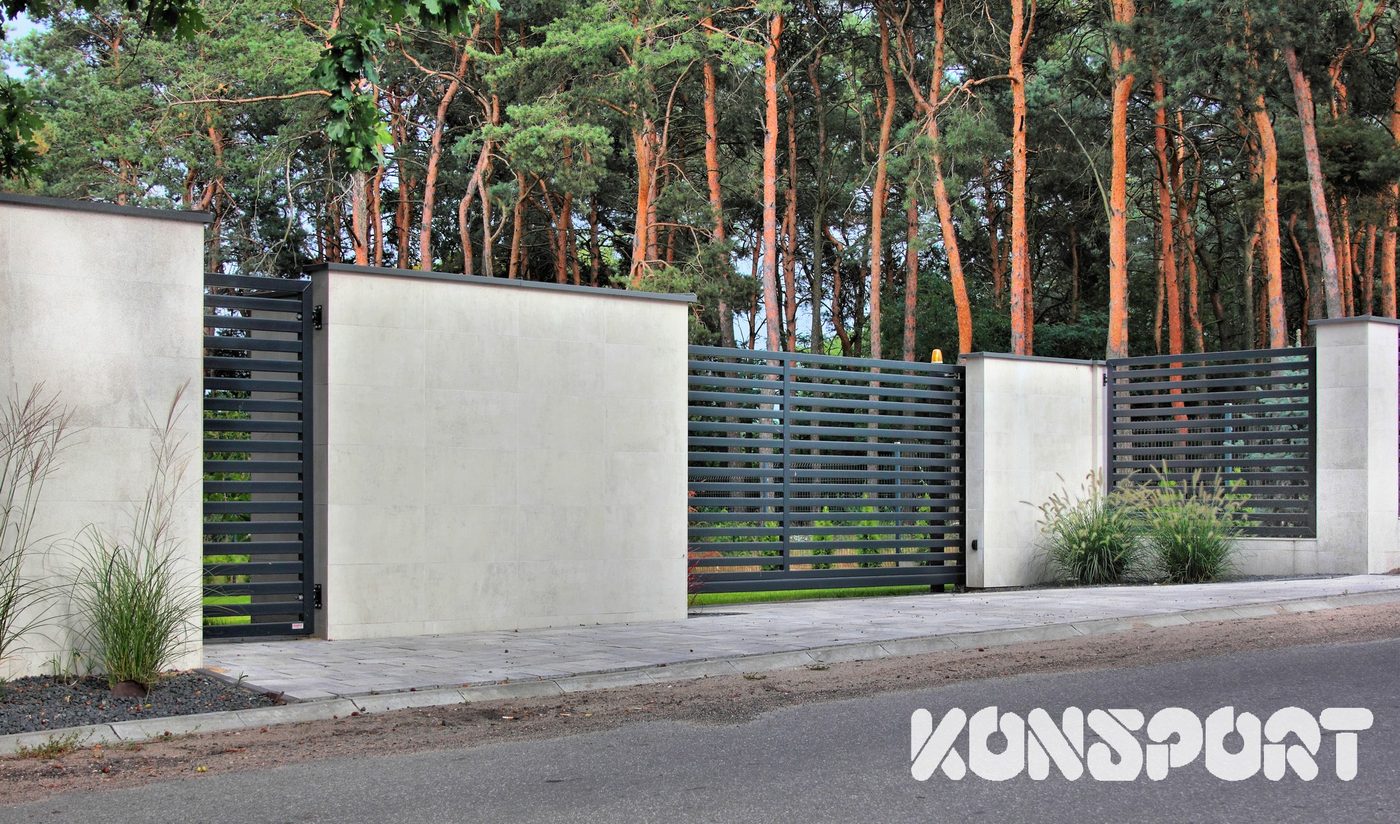 Konsport: Brama przesuwna z lameli między tynkowanymi słupkami w lesie sosnowym