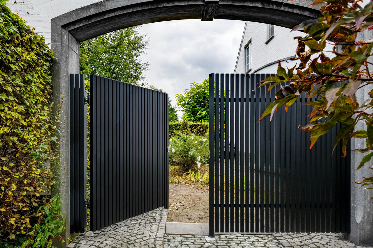 Wiśniowski: Brama z pionowych profili w murowanym łuku